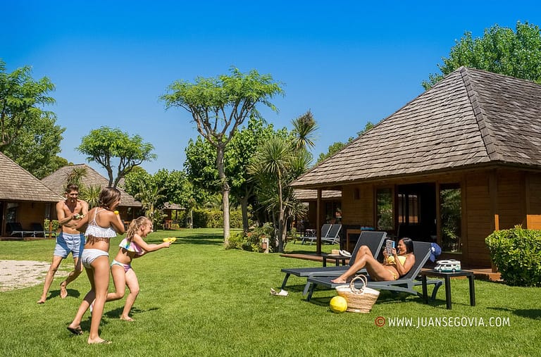 Familia jugando en el cesped frente a su bungalow en el camping Montroig Tarragona