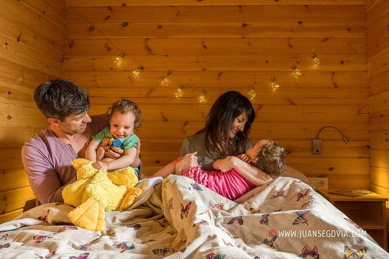 Familia con ninos jugando en la cama de un bungalow del camping de Prades