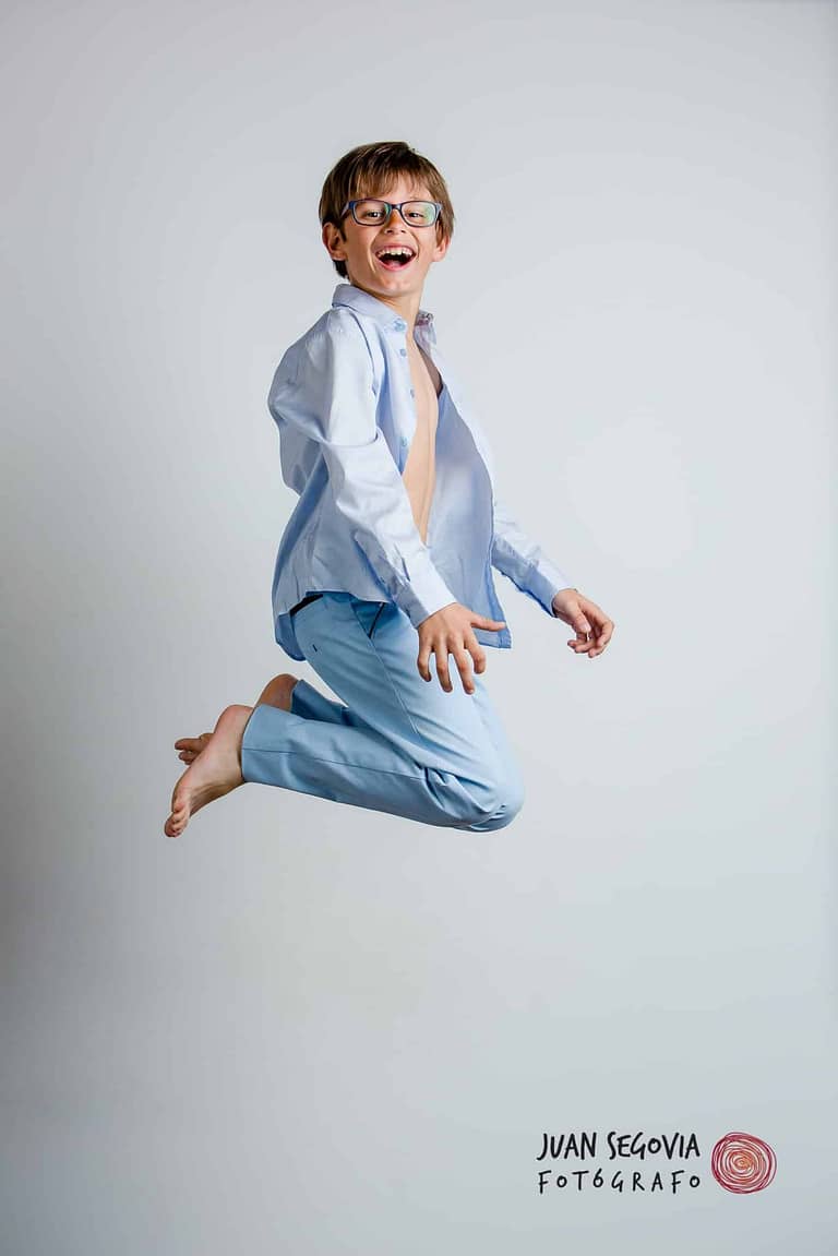 Divertida fotografía de un niño con gafas saltando, para su reportaje de comunión en estudio, por el fotógrafo Juan Segovia en Tarragona