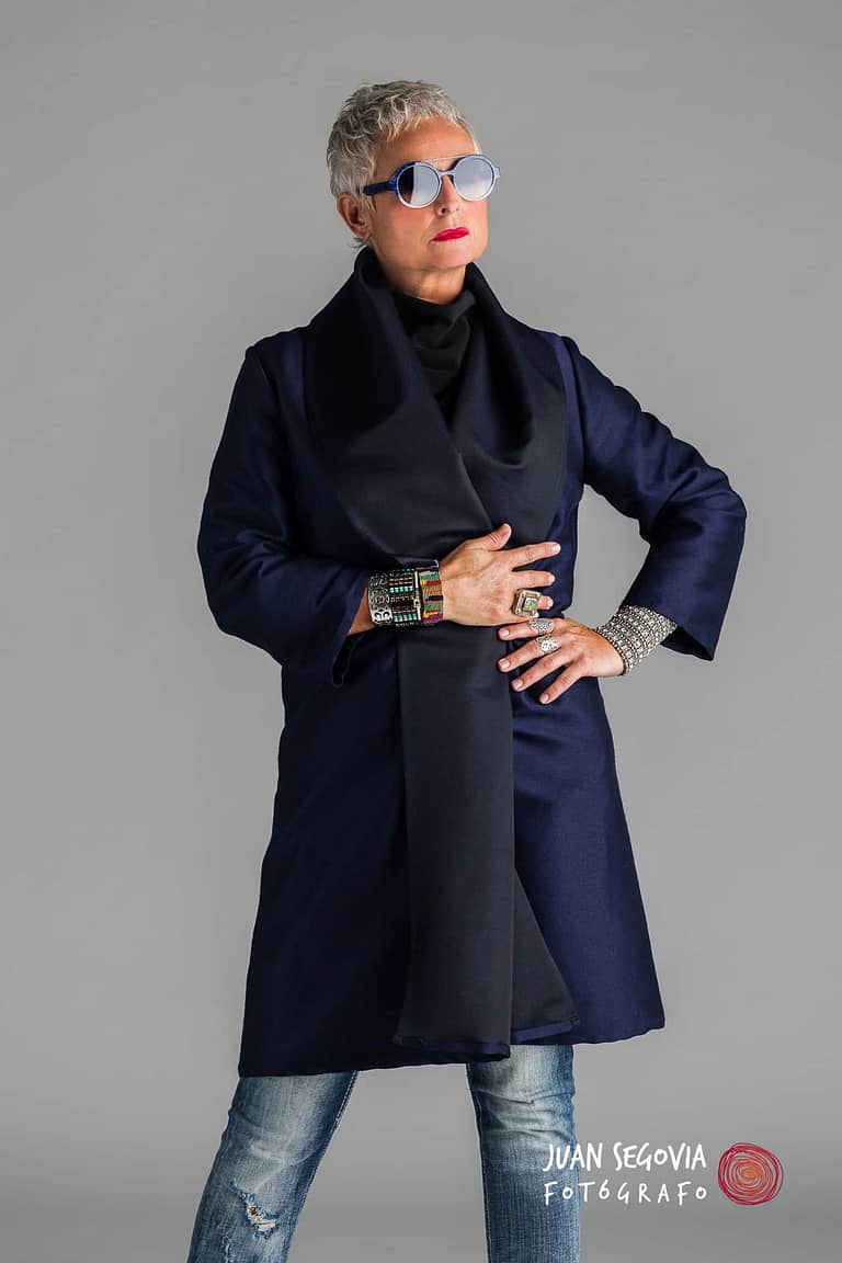 Fotografía de retrato en estudio de Cristina Lleixá posando con abrigo azul, tejanos y gafas. Fotografía de retrato por Juan Segovia, fotógrafo en Tarragona
