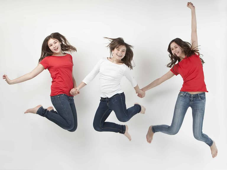 Fotografía profesional en Tarragona de familia en estudio de tres hermanas saltando.
