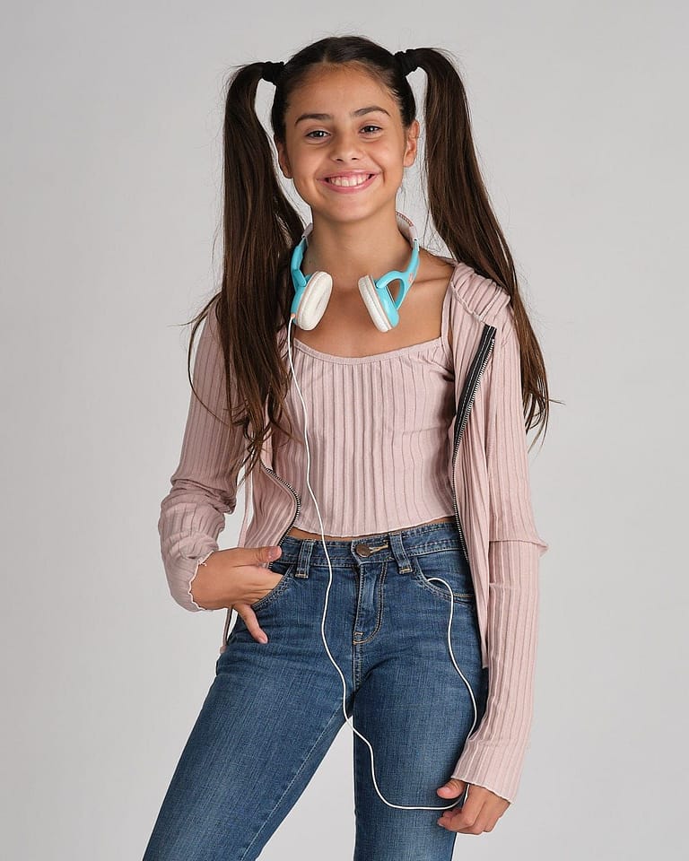 Fotografia para el book de la actriz Jasmine Serra sonriendo con coletas y auriculares en el cuello