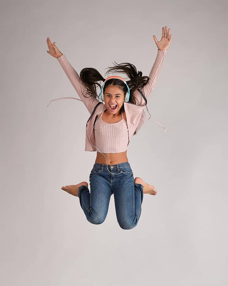 Fotografía de retrato artístico para el book de la actriz Jasmine Serra saltando y gritando con coletas y auriculares